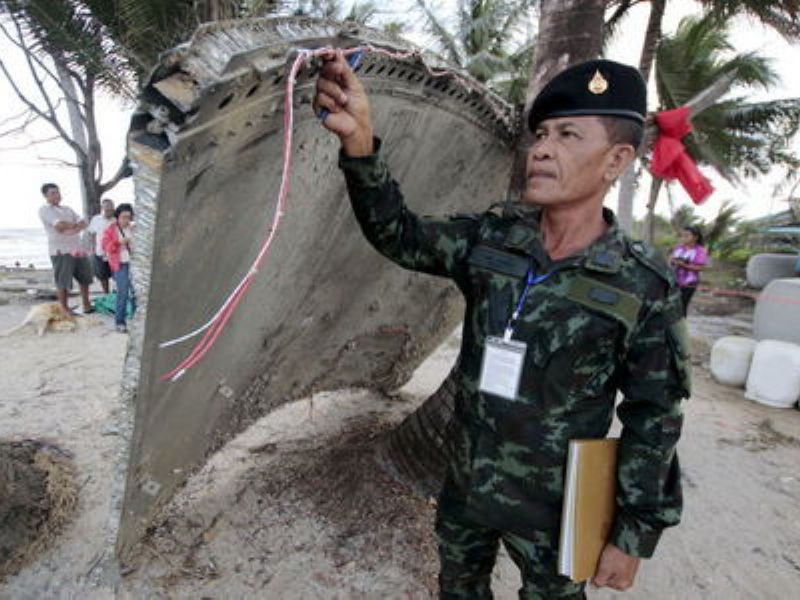 Một sĩ quan Thái Lan kiểm tra mảnh vỡ tìm thấy ở bờ biển phía nam nước này, thuộc tỉnh Nakhon Si Thammarat - Ảnh: Reuters