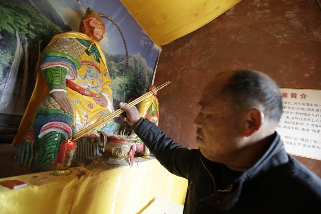 Zhang Zhijiu, cựu diễn viên xiếc khỉ, thắp nhang tại đền thờ Tề Thiên Đại Thánh - Ảnh: Reuters