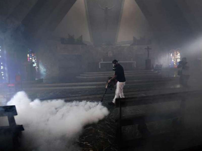 Nhân viên y tế phun thuốc diệt muỗi trong một nhà thờ tại thủ đô Caracas, Venezuela - Ảnh: AFP