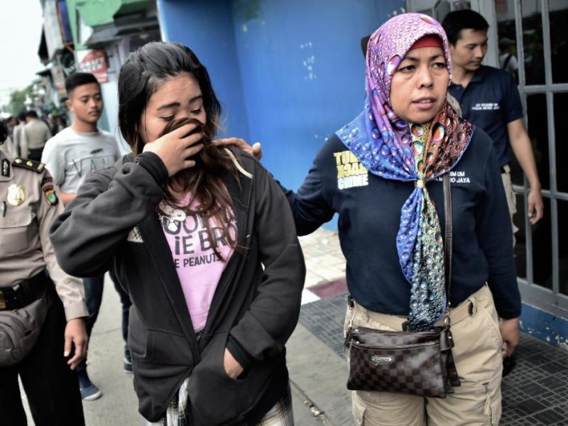 Nữ cảnh sát mặc thường phục (phải) dẫn độ một gái mại dâm (trái) trong đợt truy quét mại dâm ở thủ đô Jakarta - Ảnh: AFP