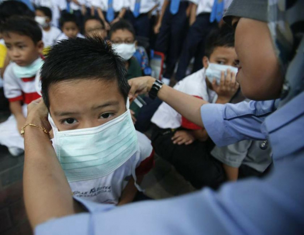 Học sinh phải đeo khẩu trang tránh khói mù do đốt rừng từ Indonesia bay sang - Ảnh: Reuters