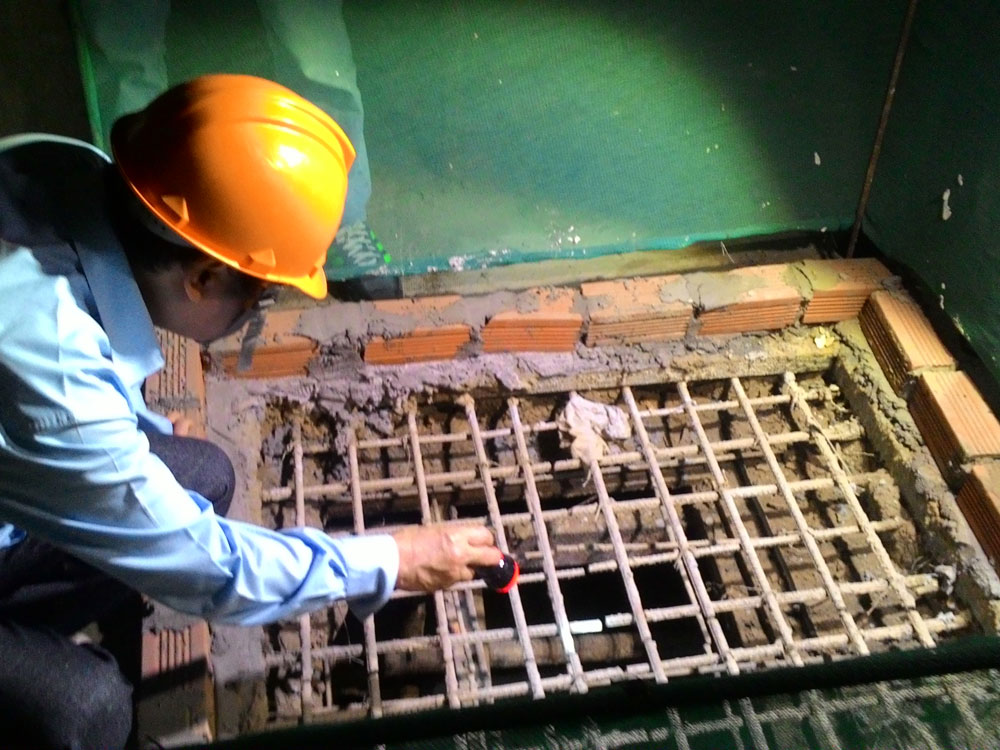 Ông Trần Đắc Phu soi đèn kiểm tra các ổ chứa lăng quăng trong khu công trình xây dựng trên địa bàn Q.Tân Phú - Ảnh: Lương Ngọc