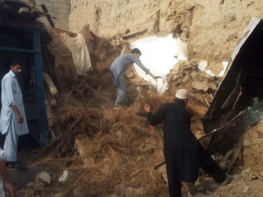 Người dân ở vùng Dir, Pakistan đào bới đống đổ nát để tìm kiếm nạn nhân bị chôn vùi - Ảnh: AFP