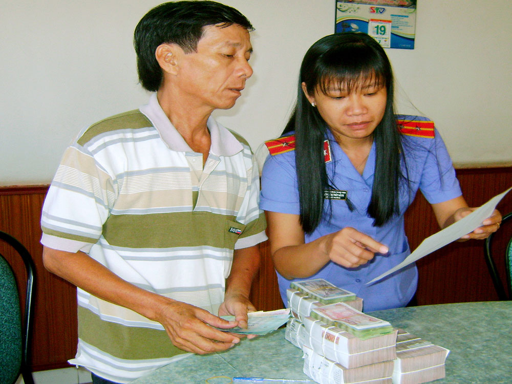 Ông Phạm Văn Lé (bên trái) nhận tiền bồi thường oan sai - Ảnh: Huyền Trinh