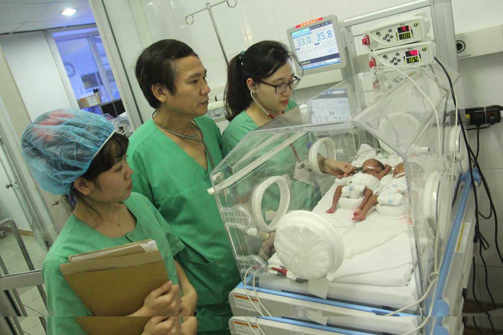 Thầy thuốc Ưu tú, bác sĩ nhi khoa Nguyễn Ngọc Lợi (giữa) kiểm tra sức khỏe cho các bé sơ sinh - Ảnh: Thúy Hằng
