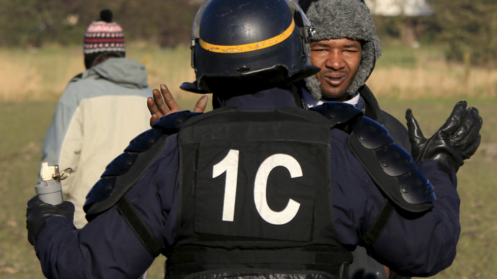 Cảnh sát chống bạo động tại Calais ngăn một người nhập cư đang cố lên phà đến Anh - Ảnh: Reuters