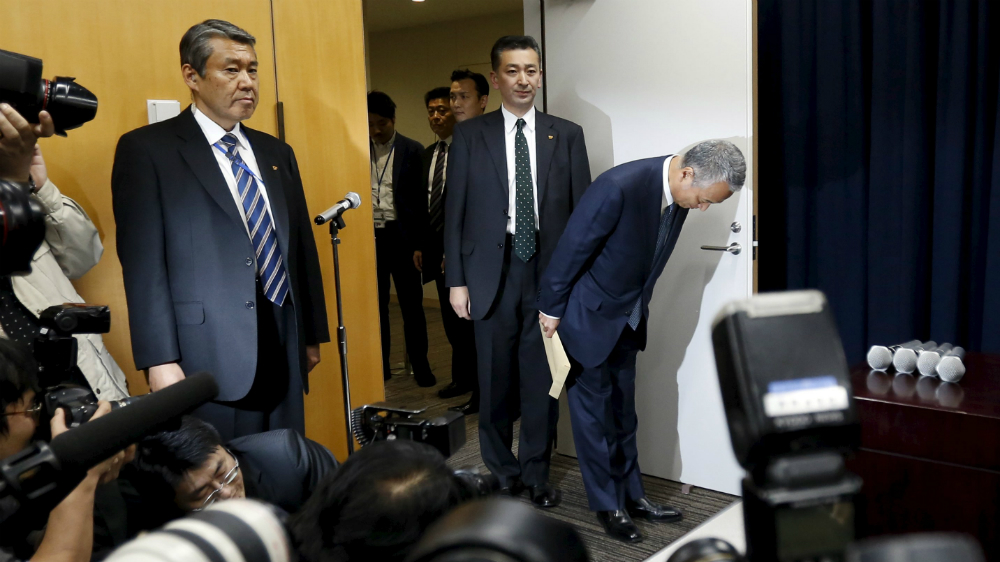Bộ trưởng Chính sách kinh tế và tài chính Nhật Akira Amari cúi chào trong buổi họp báo tuyên bố từ chức - Ảnh: Reuters