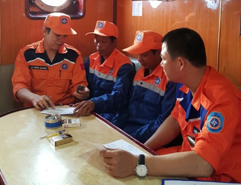 Hai ngư dân (ngồi giữa) được cứu nạn kịp thời và đưa lên tàu SAR27-01 về bờ - Ảnh: Nguyễn Chung 