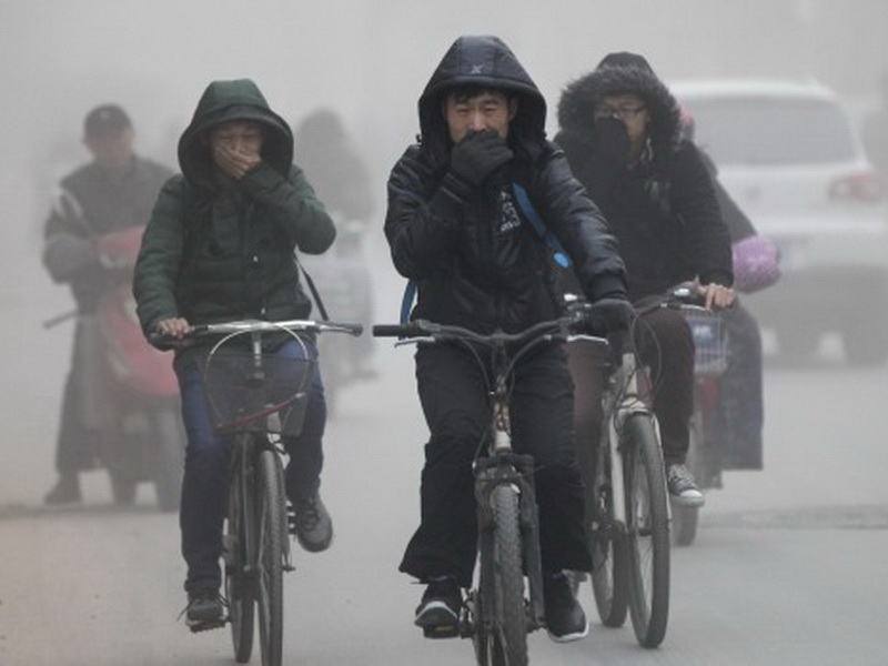 Người dân thành phố Trịnh Châu (Trung Quốc) đạp xe trong tiết trời mù sương - Ảnh: Reuters