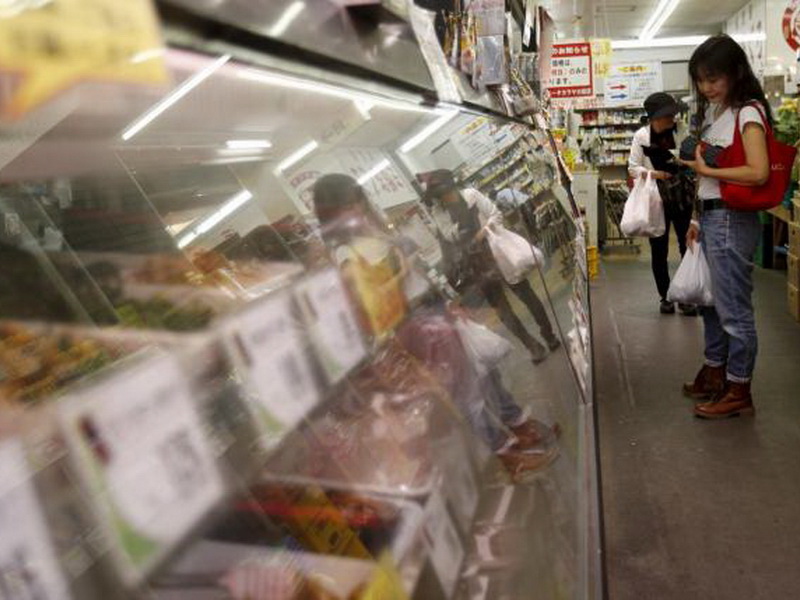 Một người phụ nữ đứng nhìn quầy thực phẩm chế biến tại một khu mua sắm ở Tokyo - Ảnh: Reuters