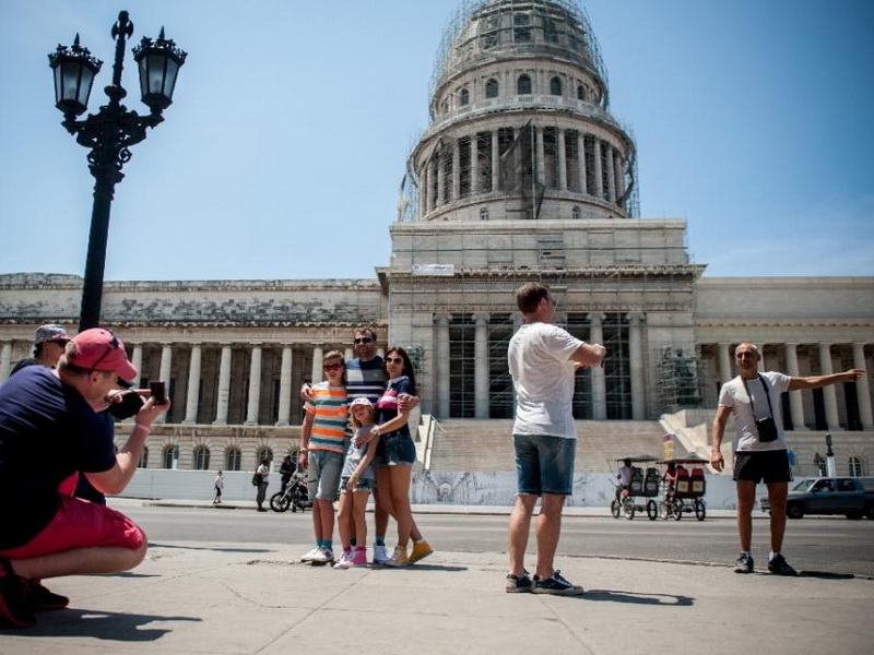Du khách Mỹ tạo dáng chụp ảnh trước Tòa nhà Quốc hội Cuba ở thủ đô Havana - Ảnh: AFP
