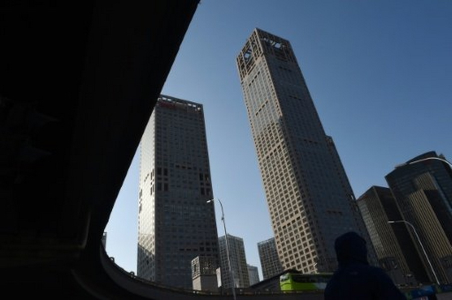 Một khách bộ hành đi ngang qua các tòa nhà cao tầng tọa lạc tại trung tâm Bắc Kinh (Trung Quốc) - Ảnh: AFP