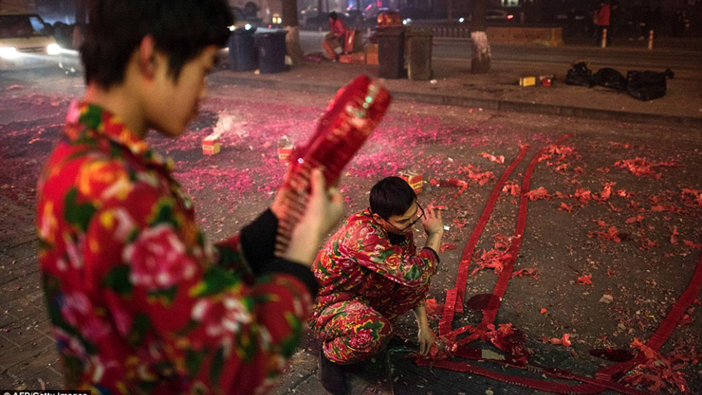 Nhân viên một nhà hàng ở Bắc Kinh đang nối hàng loạt dây pháo để đốt, đón giao thừa Bính Thân - Ảnh: AFP