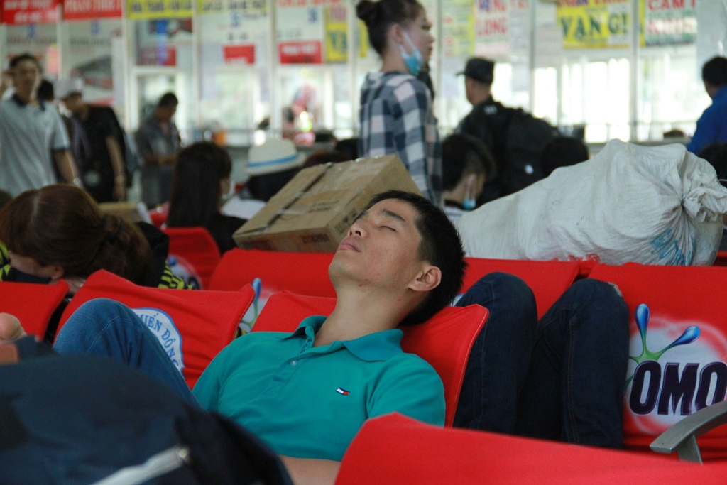 Hành khách ngủ lịm bên ghế chờ xe về quê - Ảnh: Phạm Hữu