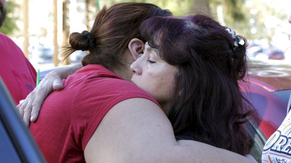 Hai người phụ nữ an ủi nhau sau vụ xả súng làm chết 14 người ở California hôm 2.12 - Ảnh: Reuters