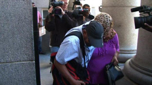Người phụ nữ bị kết tội bắt cóc (áo tím) giấu mặt trước các ống kính để bảo vệ sự riêng tư cho đứa con nuôi - Ảnh: AFP