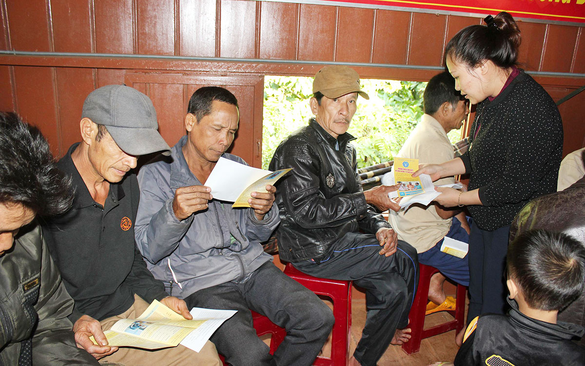 Người dân xã Ea Tu, TP.Buôn Ma Thuột nhận tờ rơi thông tin, hướng dẫn về BHYT hộ gia đình 
