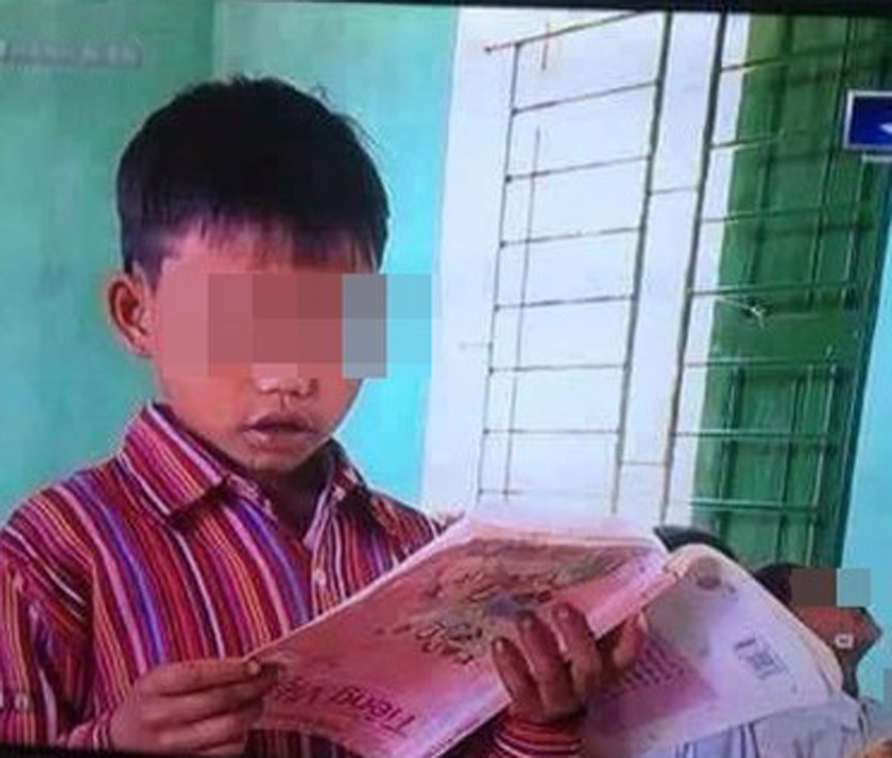 Hình ảnh em học sinh cầm sách ngược trong đoạn phóng sự - Ảnh: TL