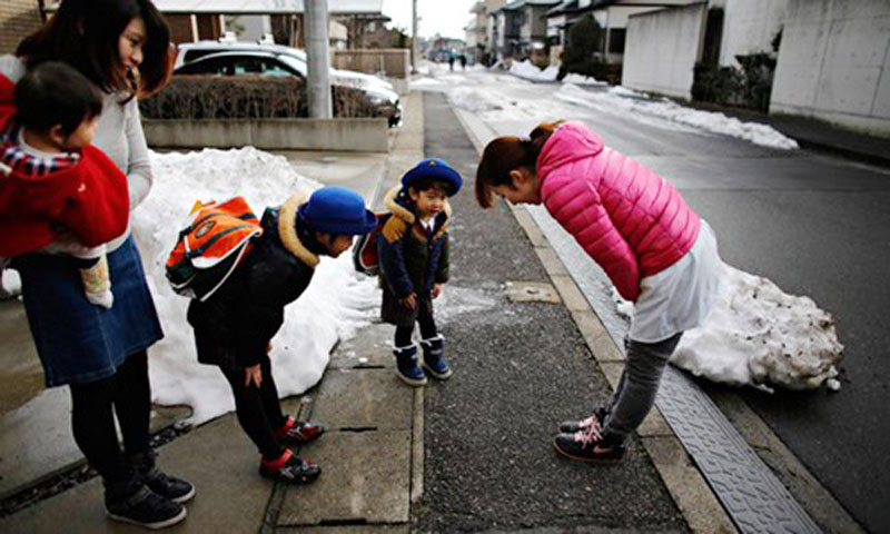 Người Nhật thường cúi gập người để chào, thể hiện sự tôn trọng nhau. Trong ảnh, cả cô giáo và học sinh đều cúi chào nhau - Ảnh: Reuters
