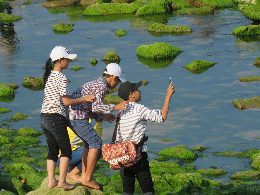 Du khách leo lên trên tảng đá phủ rêu chụp hình rất nguy hiểm