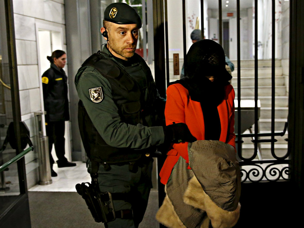 Một nghi phạm đang bị cảnh sát Tây Ban Nha áp tải ra khỏi chi nhánh ICBC ở Tây Ban Nha - Ảnh: Reuters