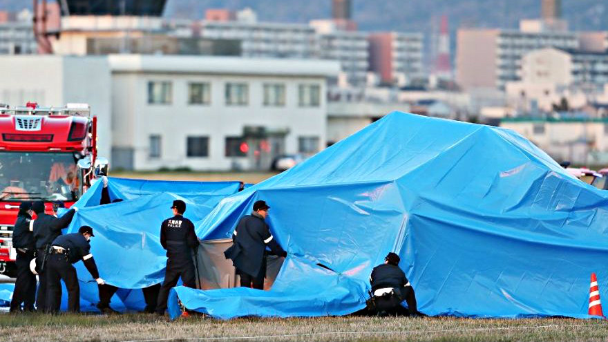 Cảnh sát bao phủ chiếc máy bay rơi bằng tấm bạt xanh - Ảnh: AFP