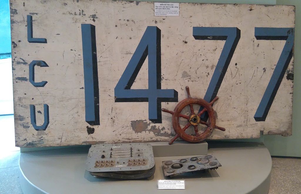 Biển số tàu LCU và đồng hồ điện, tay lái, bảng điện của con tàu địch thứ 100 bị đặc công hải quân đánh chìm ở Cửa Việt (Quảng Trị), tháng 12.1968. Hiện vật trưng bày tại Bảo tàng Hải quân - Ảnh chụp lại
