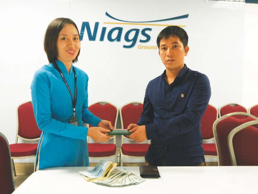Nhân viên NIAGS bàn giao tài sản bỏ quên lại cho khách - Ảnh: VNA