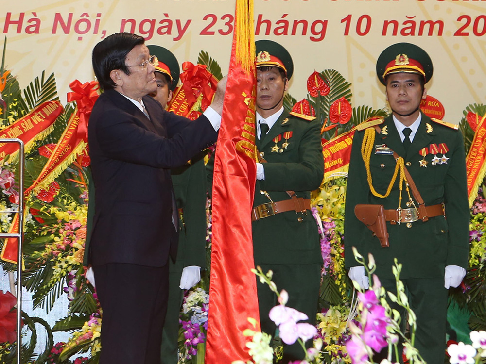 Chủ tịch nước Trương Tấn Sang gắn Huân chương Quân công hạng nhất lên Quân kỳ Quyết thắng của Tổng cục Tình báo quốc phòng VN - Ảnh: TTXVN