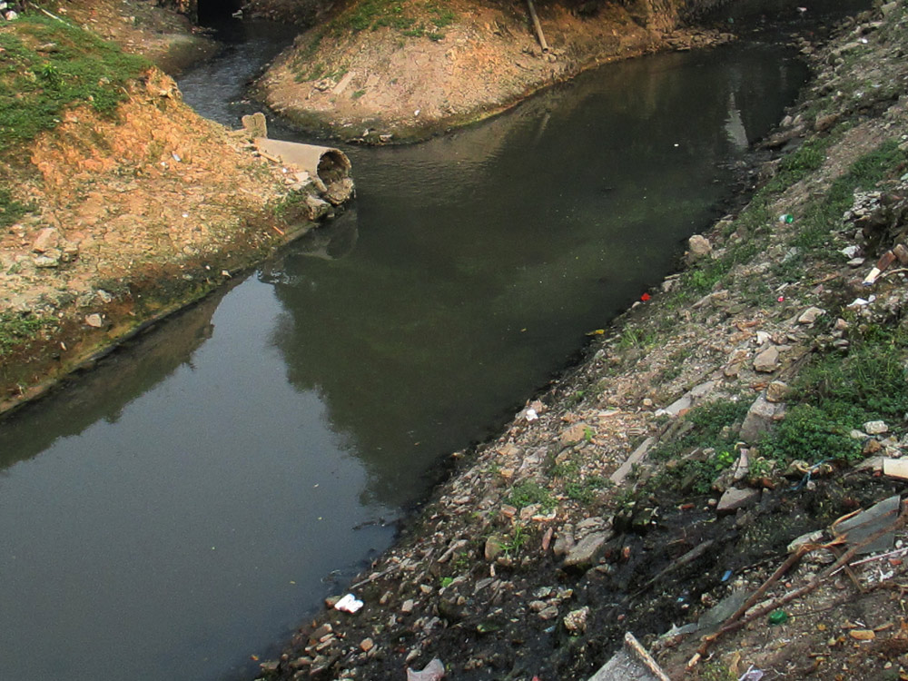 Đã từ lâu, con mương thoát nước bị ô nhiễm trầm trọng bởi rác và nước thải nhưng không được xử lý - Ảnh: Chí An