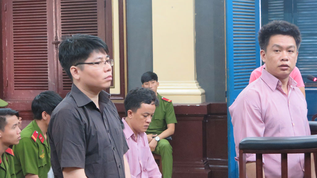 Bị cáo Lam (đứng, trái) và bị cáo Vinh đối chất tại tòa - Ảnh: Phan Thương