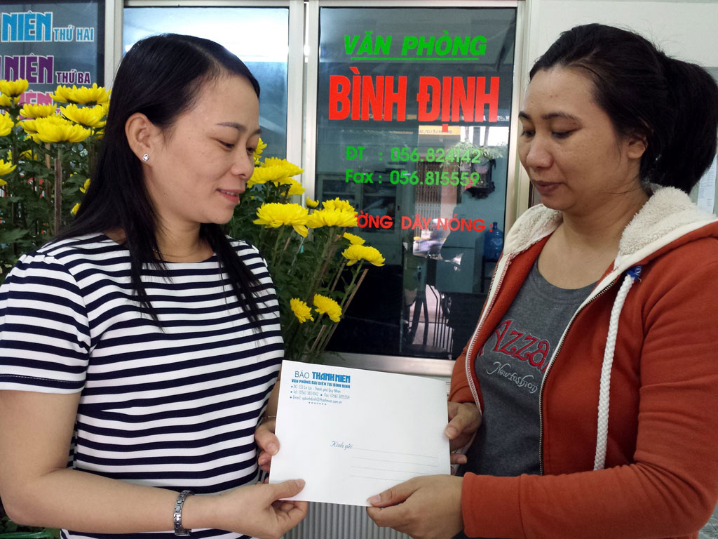 Đại diện Báo Thanh Niên tại Bình Định trao số tiền bạn đọc giúp gia đình chị Nguyễn Thị Ngà (bên phải) - Ảnh: Tâm Ngọc