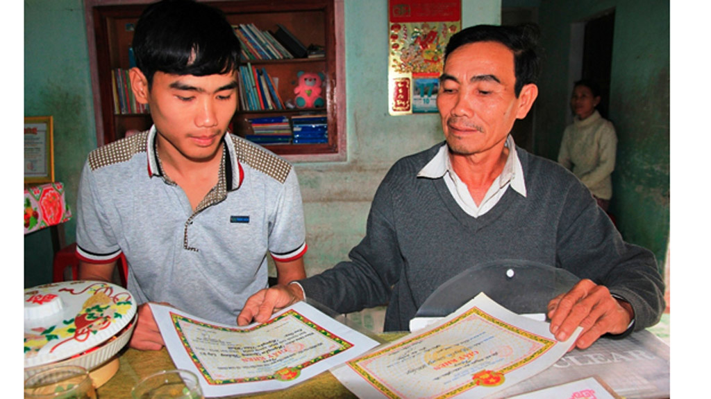 Quang Thắng (trái) cùng bố xem lại những thành tích của mình trong những năm đi học - Ảnh: H.S