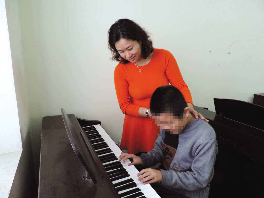 Chị Nguyệt Thu đang dạy học sinh tự kỷ đánh đàn piano