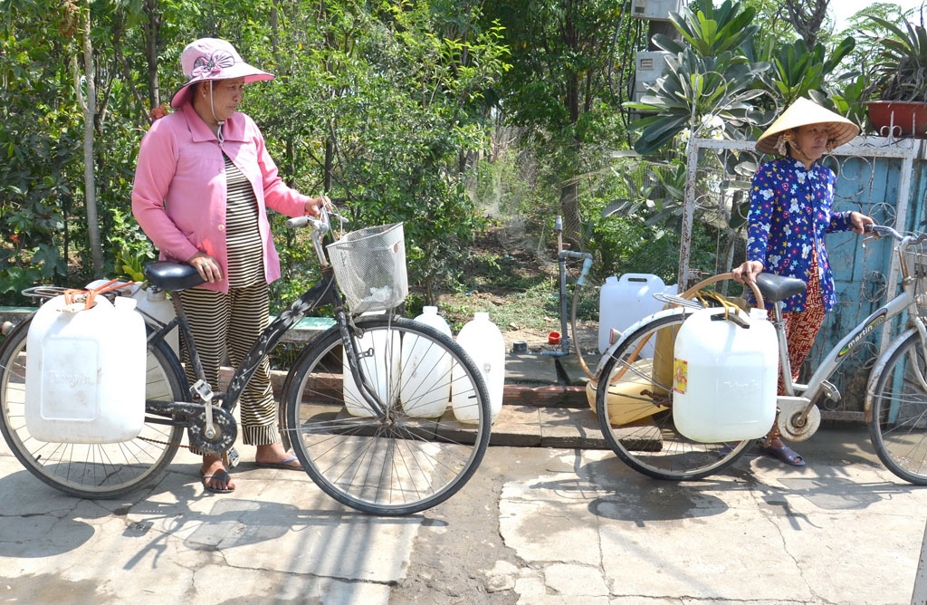 Chị em ở ấp 4 (xã Tân Phước) phải đi hơn 3 cây số để lấy nước về sử dụng - Ảnh: Hoàng Phương