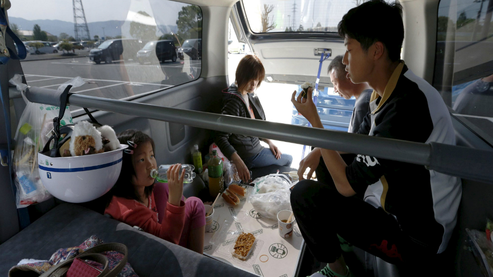 Một gia đình phải sử dụng ô tô là nơi ở sau trận động đất ở Nhật Bản - Ảnh: Reuters