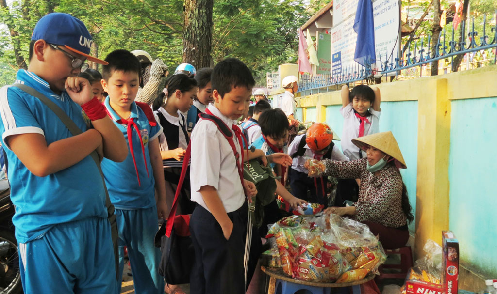 Các em nhỏ vô tư mua hàng rong trước cổng trường - Ảnh: Tuyết Khoa