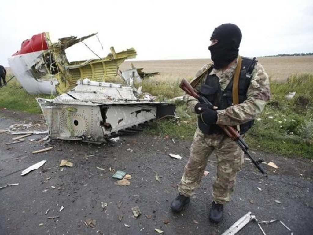 Một người lính thuộc lực lượng  ly khai ở miền đông Ukraine đứng cạnh một mảnh vỡ của MH17 - Ảnh: Reuters