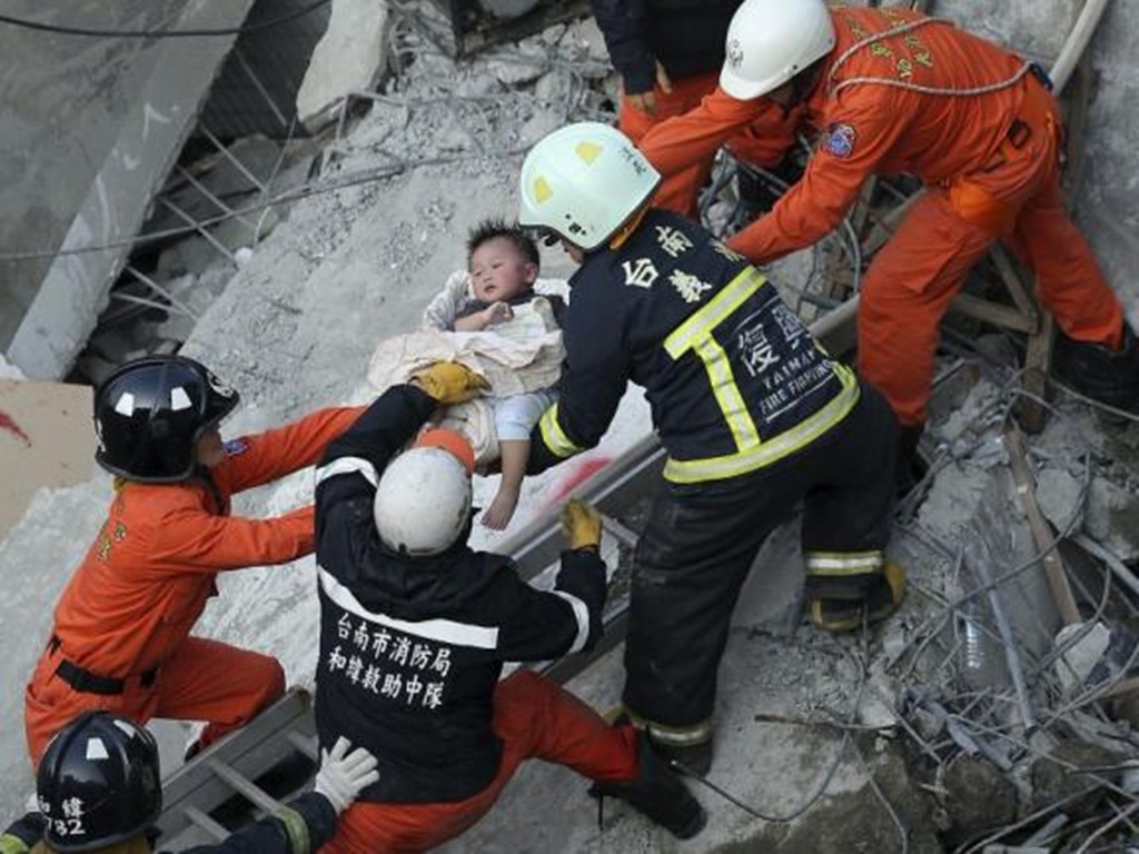 Lực lượng cứu hộ giải thoát cho một đứa bé trong khu chung cư 17 tầng hôm 6.2 - Ảnh: Reuters