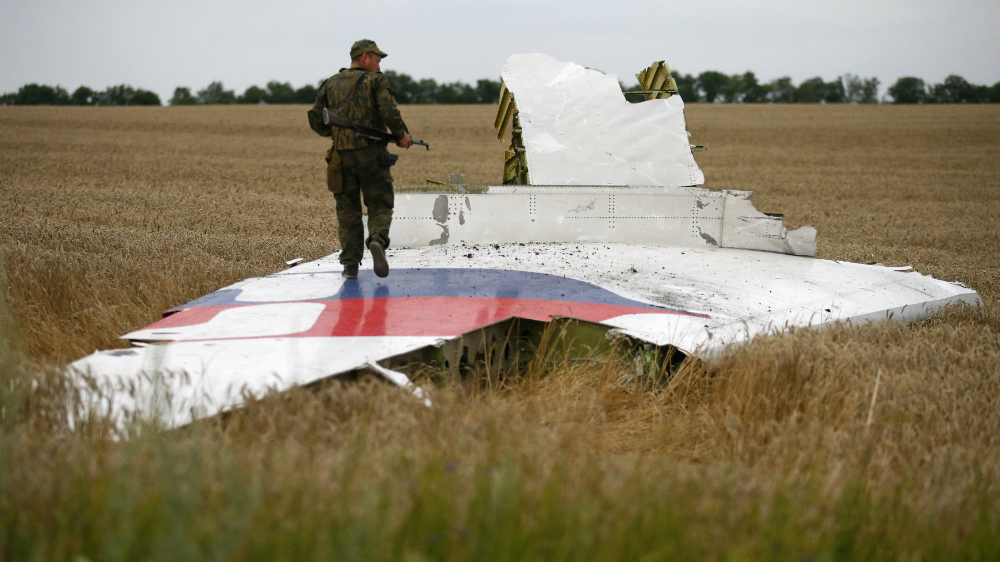 Một thành viên lực lượng nổi dậy thân Nga ở miền đông Ukraine đứng trên một mảnh vỡ của chiếc máy bay rơi MH17 xuống cánh đồng tại tỉnh Donetsk, Ukraine, tháng 7.2014 - Ảnh: Reuters