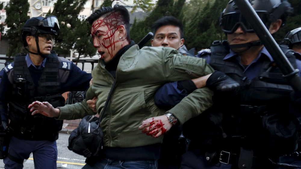 Cảnh sát áp giải một người biểu tình bị thương - Ảnh: Reuters
