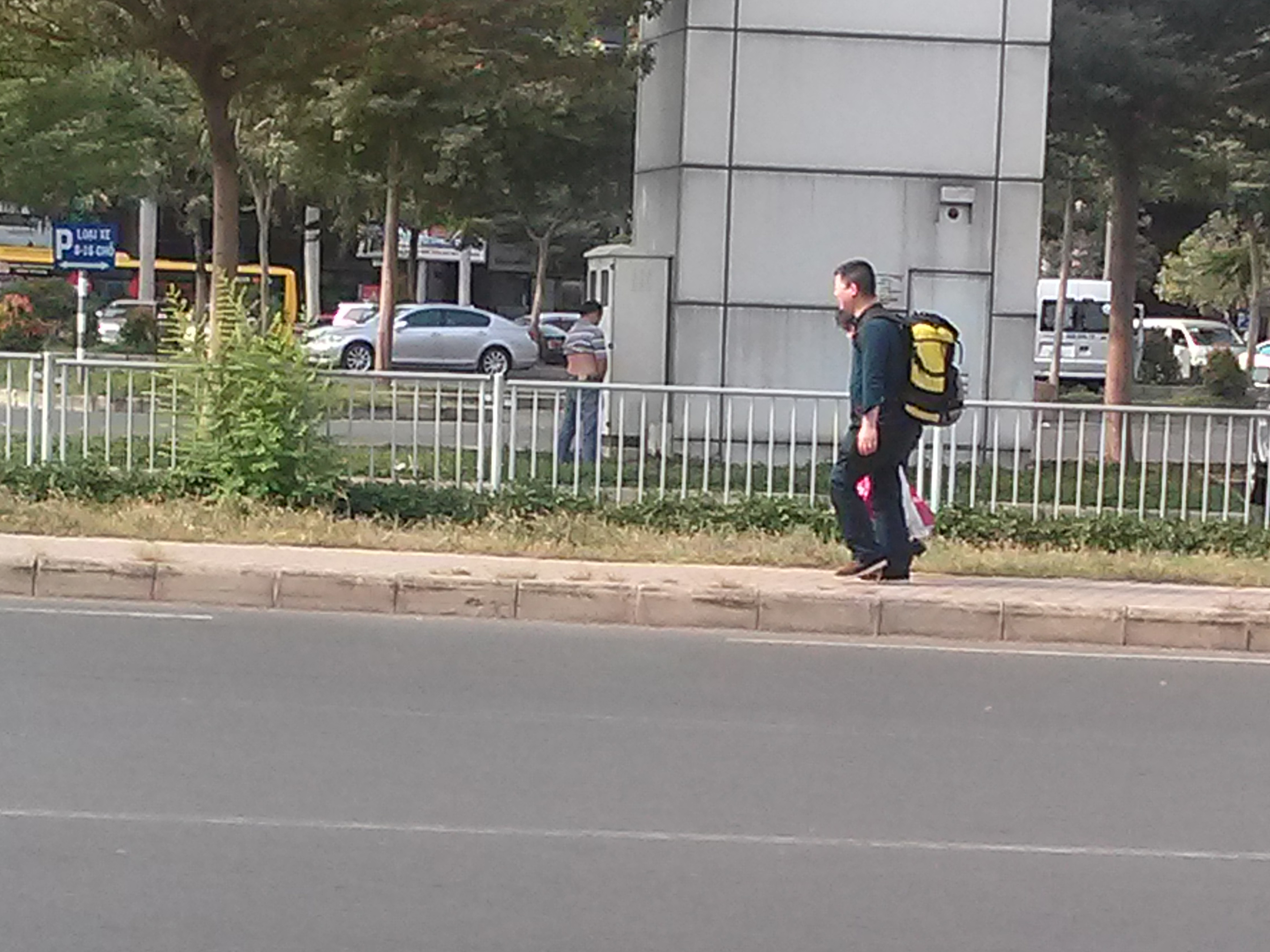 Một tài xế thản nhiên tiểu bậy ngay tại bãi xe trước mặt cặp du khách nước ngoài đang đi tới tại sân bay Tân Sơn Nhất.