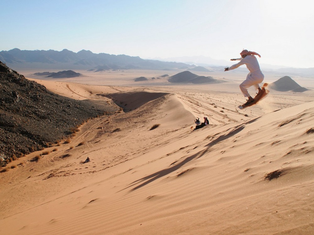 Một người đàn ông đang trượt cát tại sa mạc gần vùng Tabuk - Ảnh: Reuters