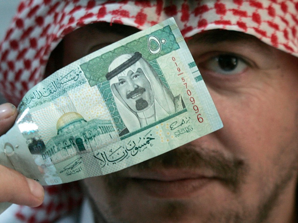 Một người đàn ông cầm tờ 50 riyal (khoảng 13,3 USD) - Ảnh: Reuters