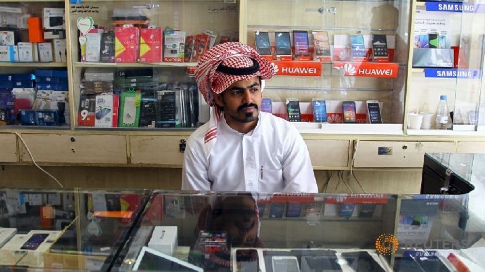 Một người bán hàng ngồi chờ khách trong cửa hàng điện thoại di động ở Riyadh (Ả Rập Xê Út) - Ảnh: Reuters