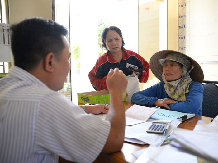 Cán bộ phường hướng dẫn người dân gia hạn thẻ BHYT - Ảnh: Lam Ngọc