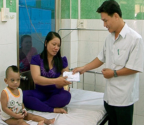 Ông Lê Quốc Anh, Phó Chủ tịch UBND xã Phong Thạnh Đông A trao tiền hỗ trợ bé Khôi - Ảnh: Trần Thanh Phong
