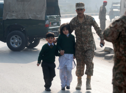  Binh sĩ Pakistan đưa các em học sinh khỏi hiện trường vụ tấn công ở Peshawar hôm 16 tháng 12 - Ảnh: Reuters
