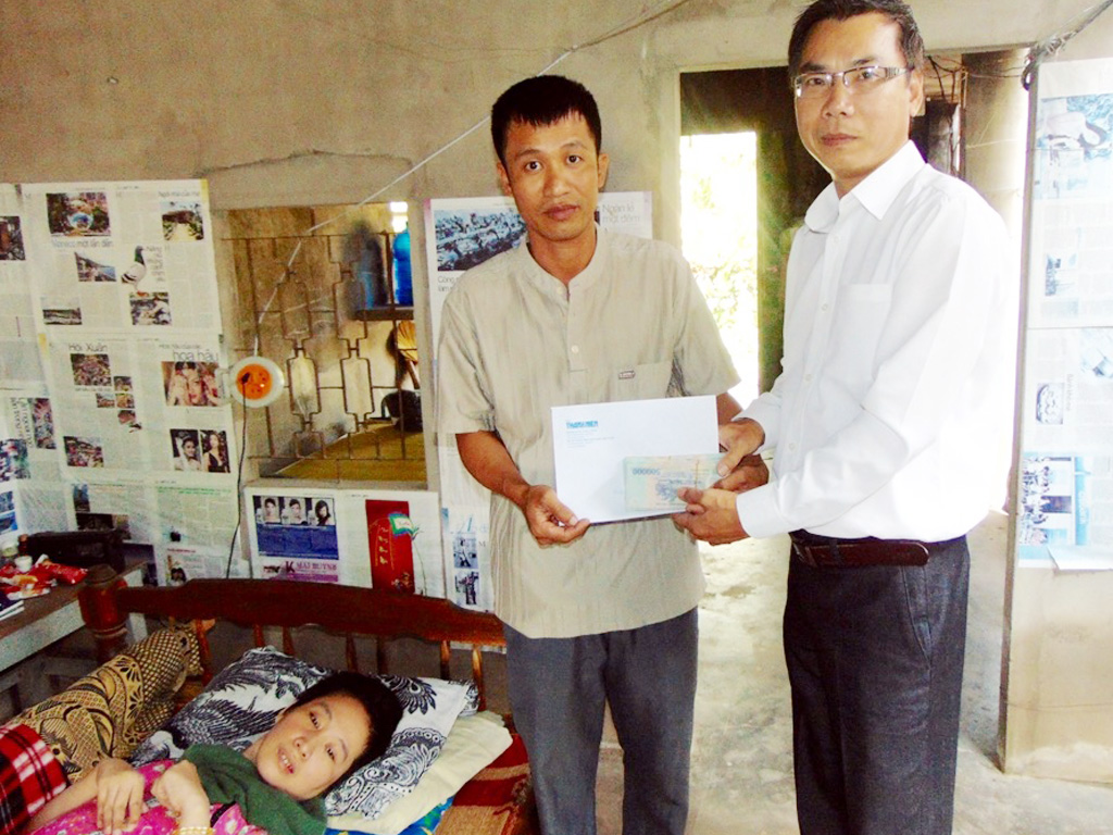 Đại diện Báo Thanh Niên (phải) trao tiền cho gia đình cô Phạm Thị Luyên