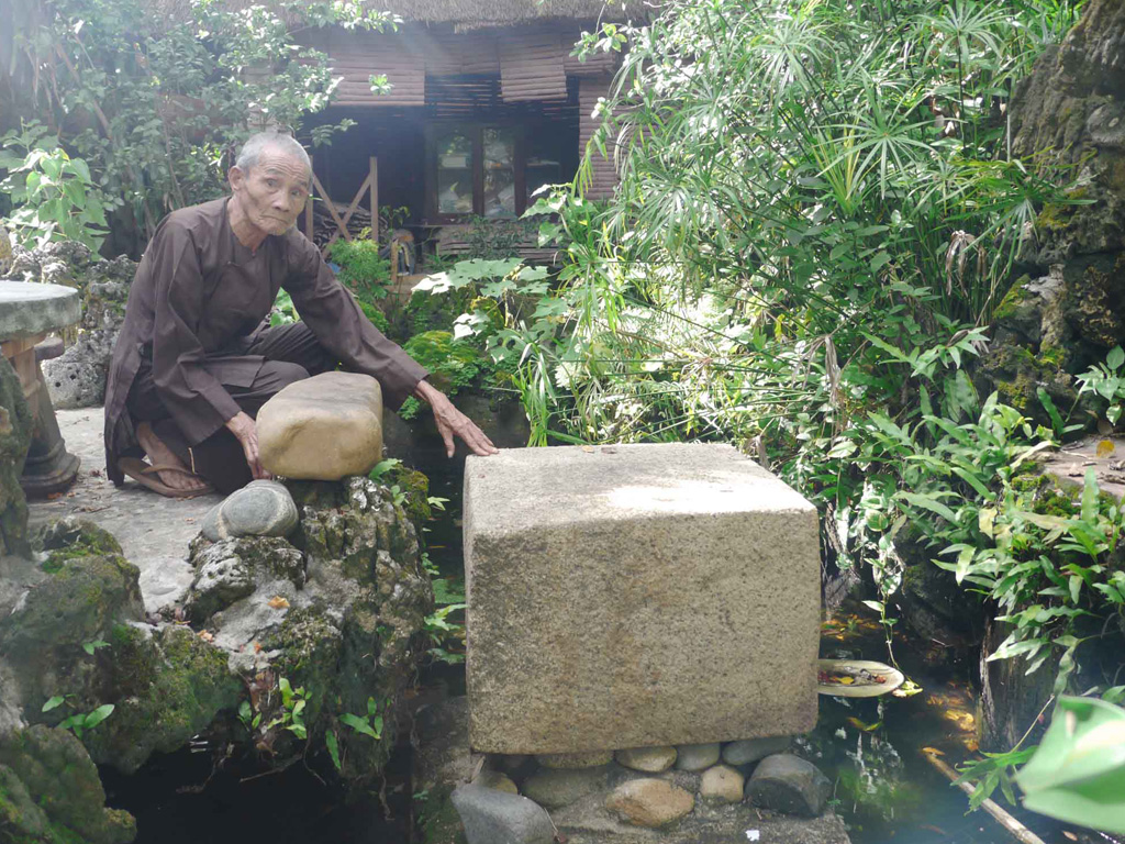 Ông Phạm Thứng bên cạnh “hòn đá bí ẩn” trong chùa Hương Quang - Ảnh: Hoàng Trọng